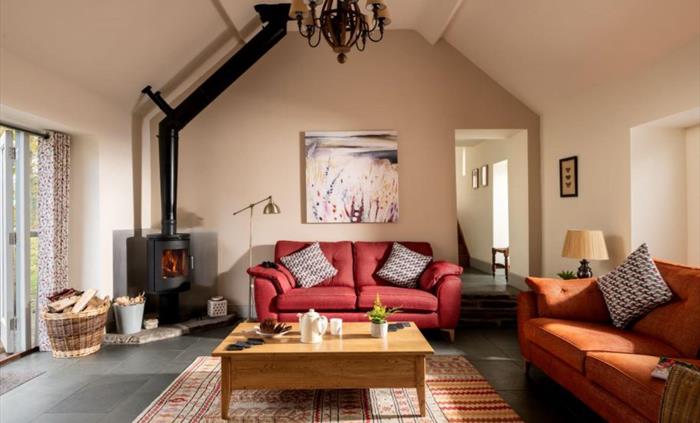 A spacious living area that has double doors opening out onto the decking . Complete with a cosy log burner